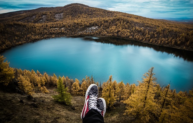 someone sitting by a lake with a pair of running shoes